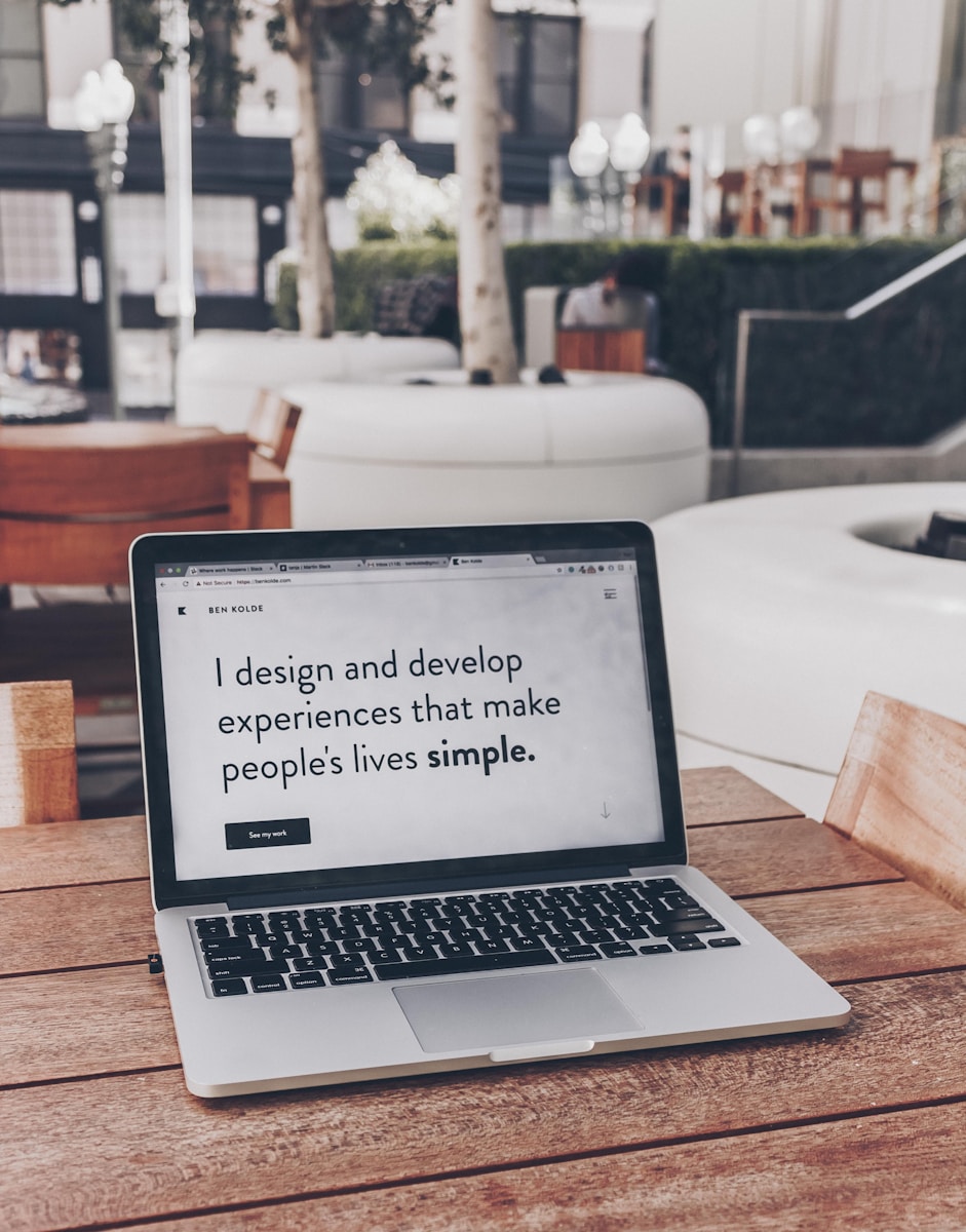 A laptop displaying the text "I design and develop experiences that make people's lives simple." The large black font on a plain white screen is an example of minimalist web design.